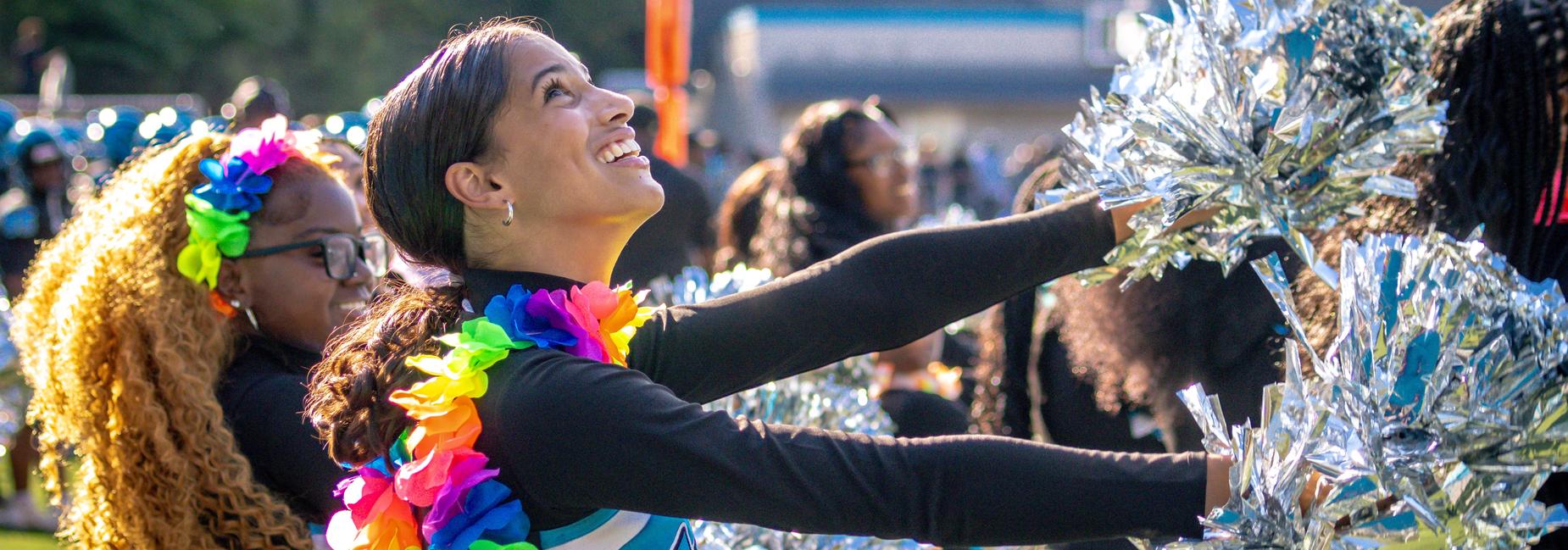 A cheerleader smiles with a colorful boa around her shoulders