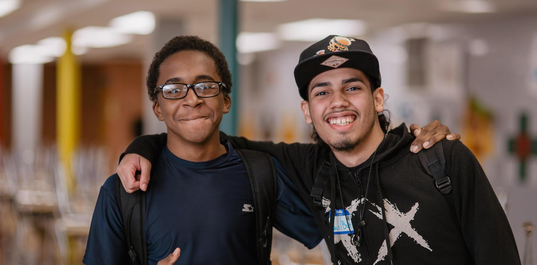 Two students pose with their arms around each other's shoulders