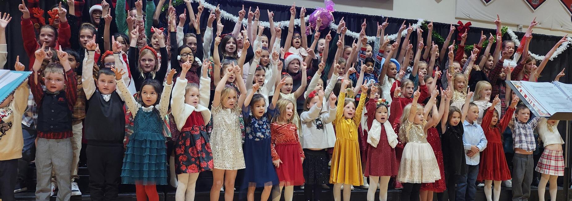 Children in festive clothing performing together at a holiday concert.