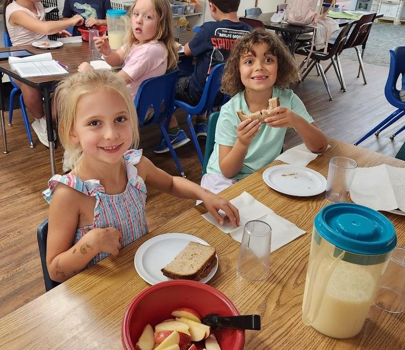 young students eating snacks family style