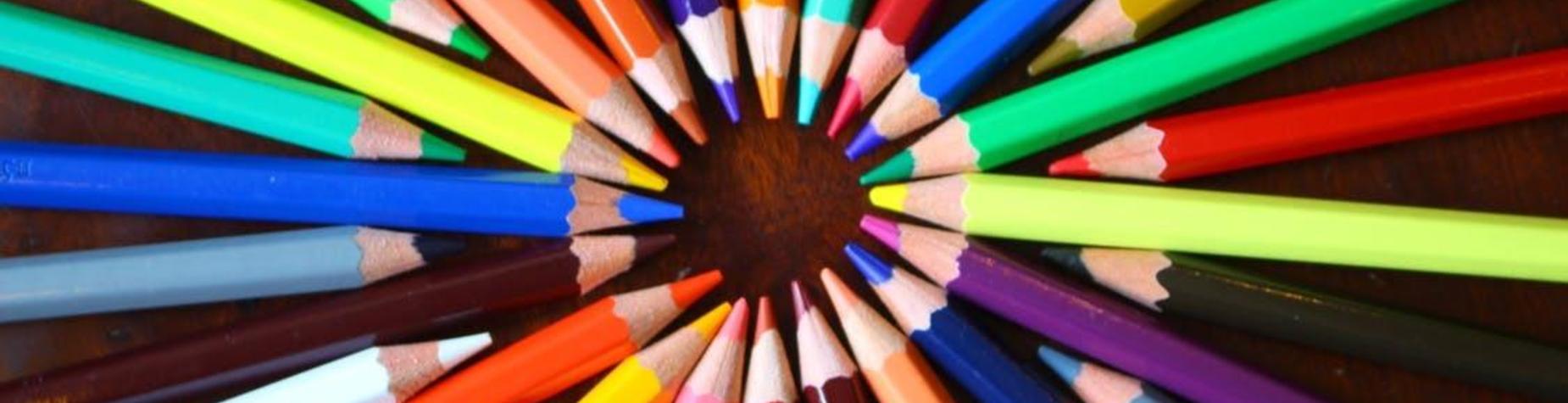 Colorful pencils arranged in a circular pattern on a wooden surface.