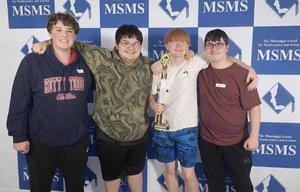 Group of four students holding a trophy