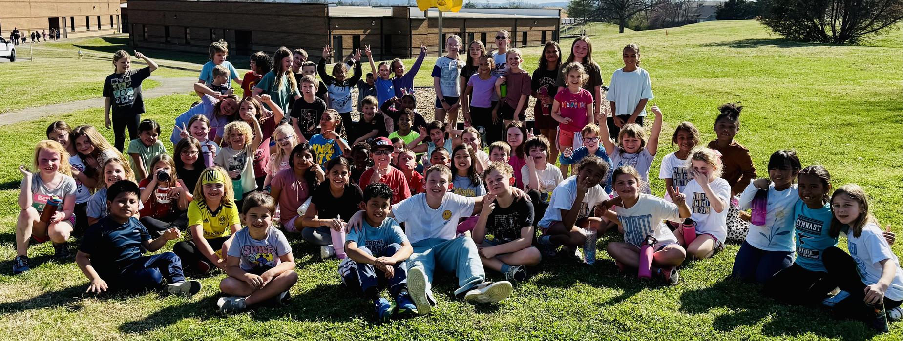 Group of diverse children posing happily on a grassy field.