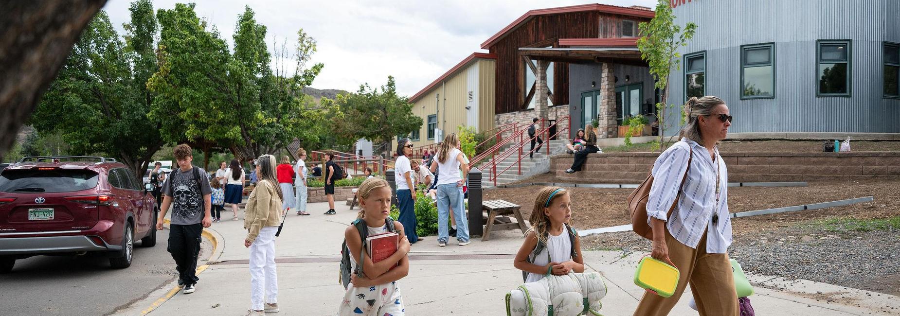 People walking outside a school building on a busy day.
