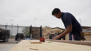 A THS construction student cuts wood for the Tiny House