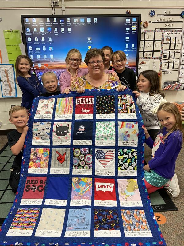 Saundra's first grade class posing with their class quilt.