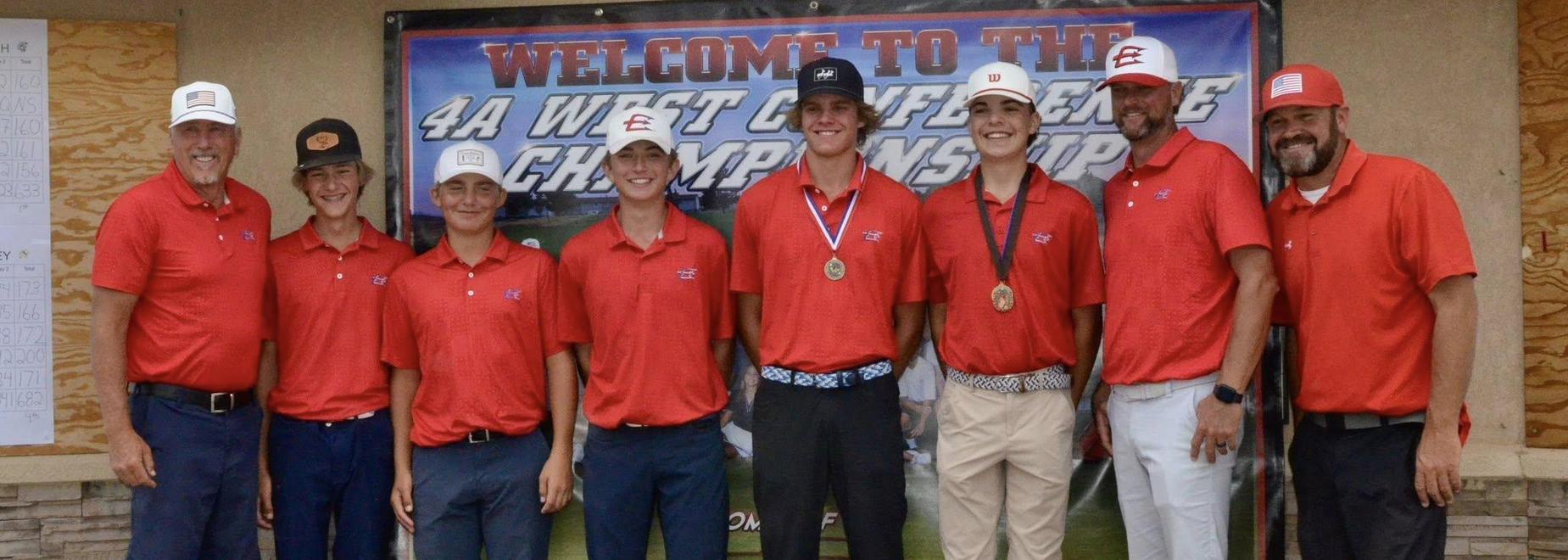 Group of seven golfers in red shirts posing with medals and a championship sign.