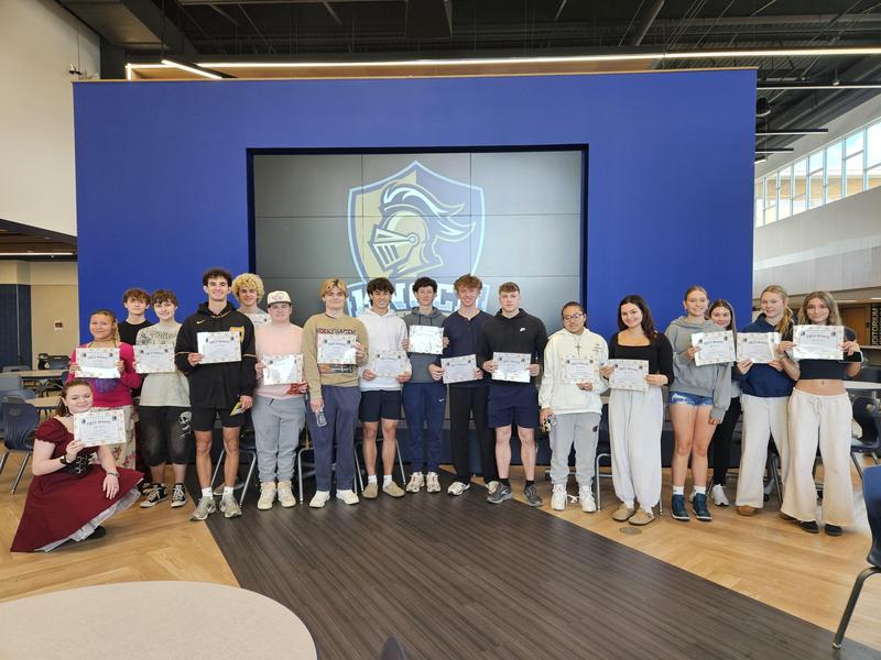 group of students holding certificates in front of knoch head on screen