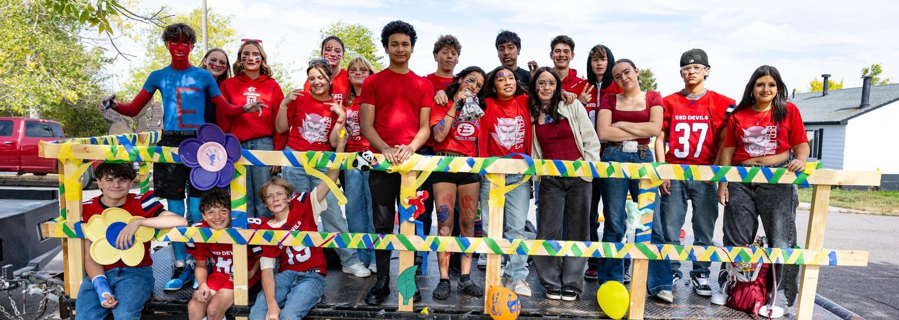 A group of people in red shirts and costumes pose on a decorated float.