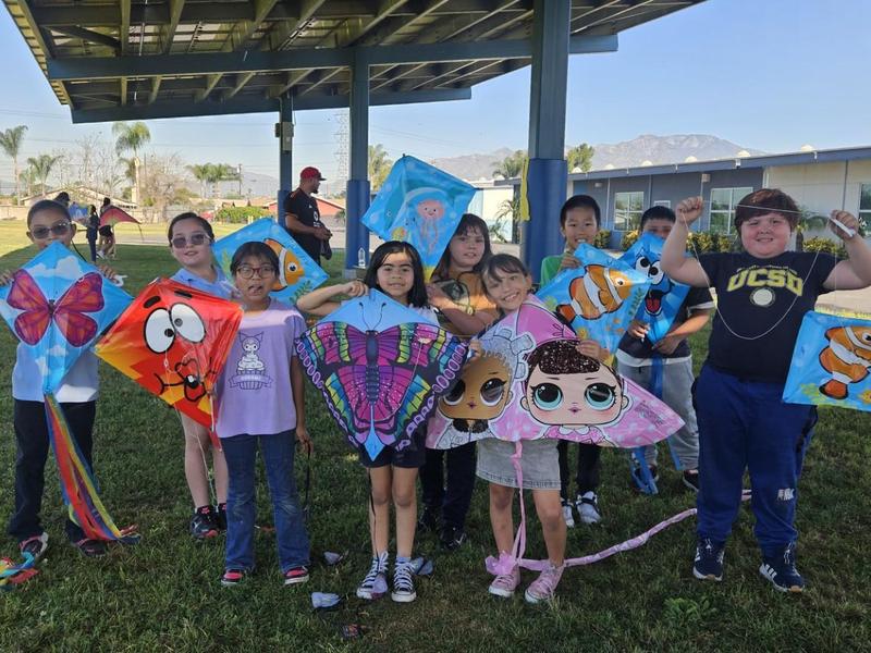 A group of children holding colorful kites under a shelter.
