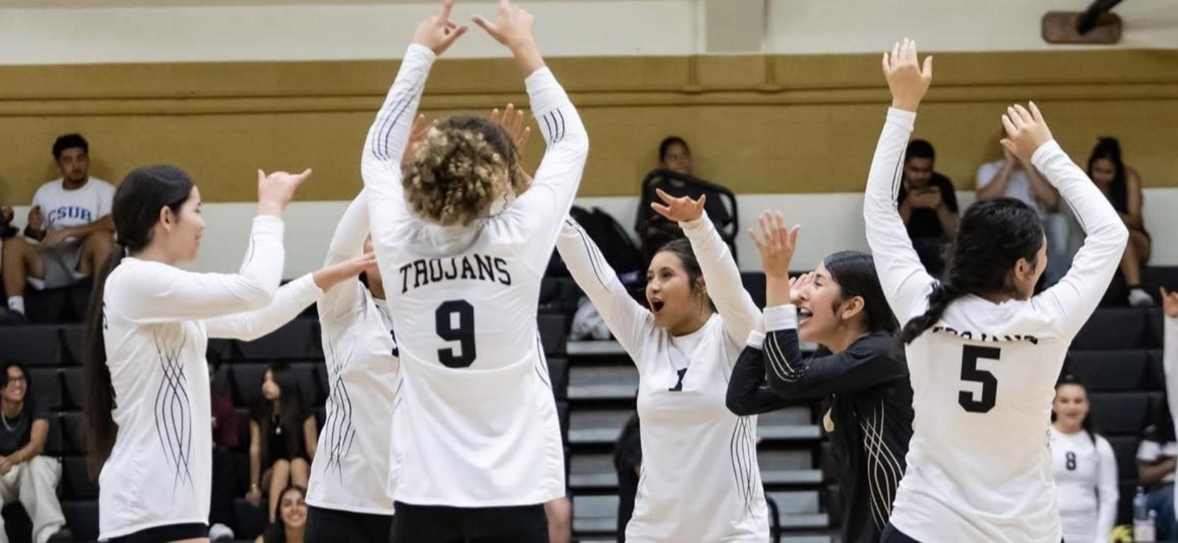 Volleyball team celebrating a point in a gymnasium.