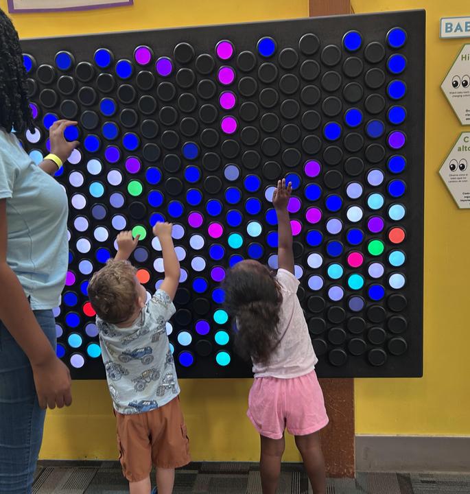 children and teacher playing with lights