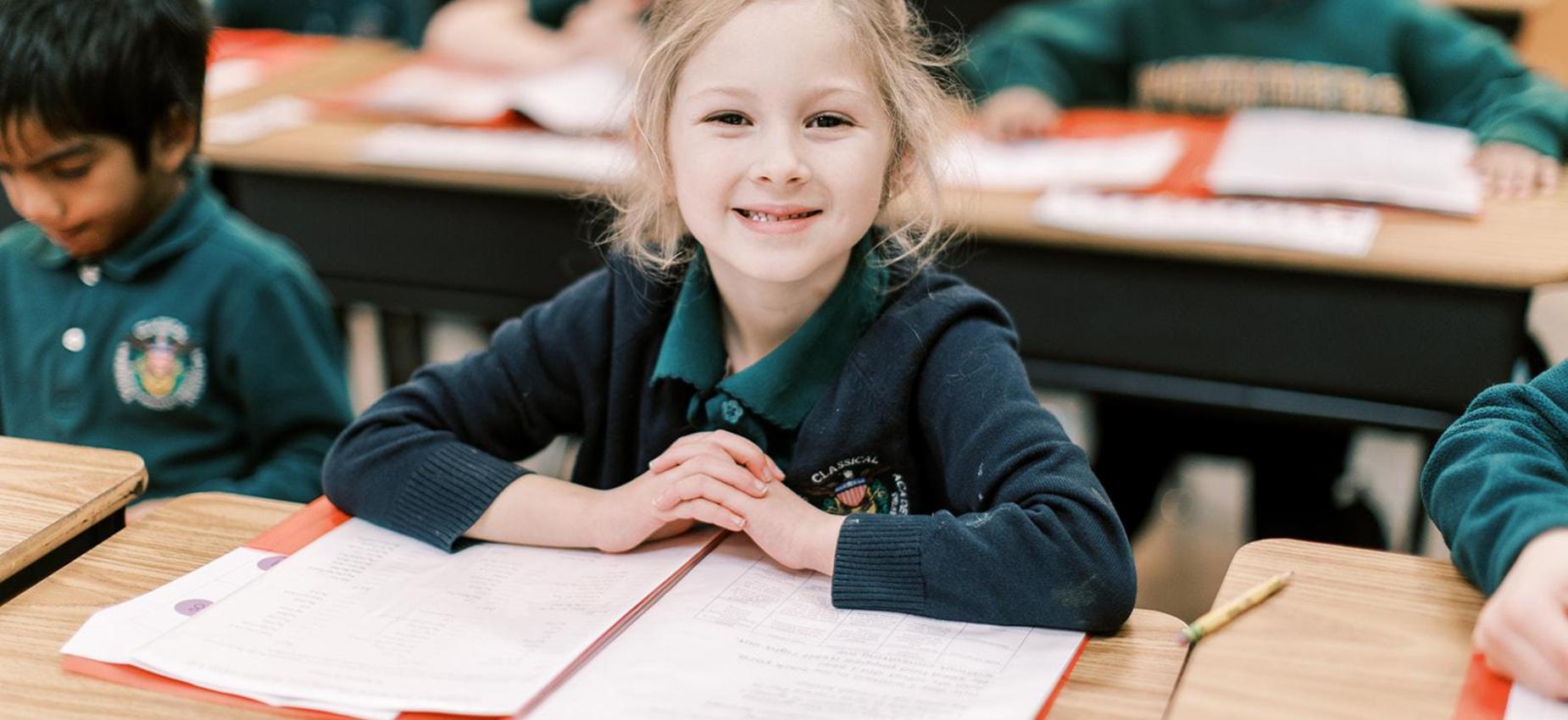 Smiling elementary student reads at her desk