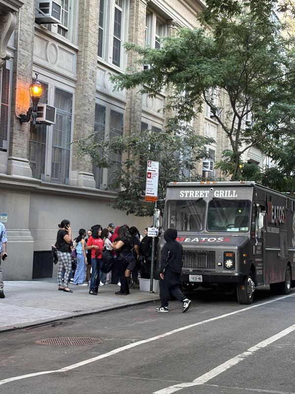 A food truck labeled 'Street Grill' with a line of people waiting.
