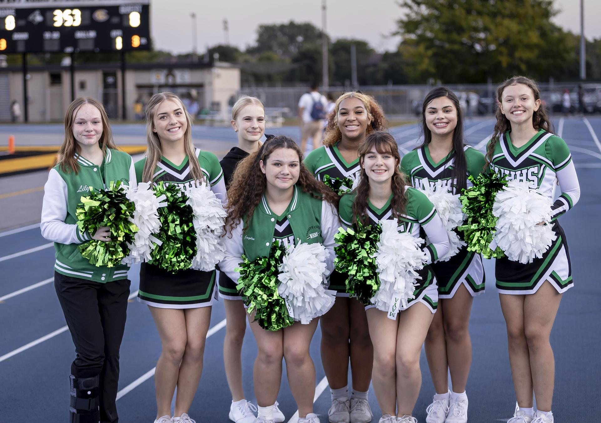 Cheer team on the sideline with their poms