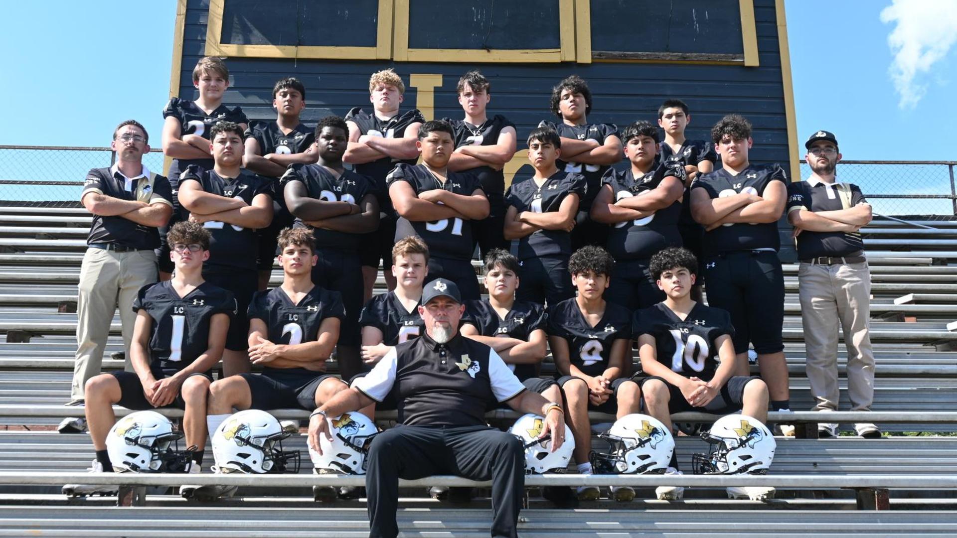 A high school football team posing together on bleachers with coaches.