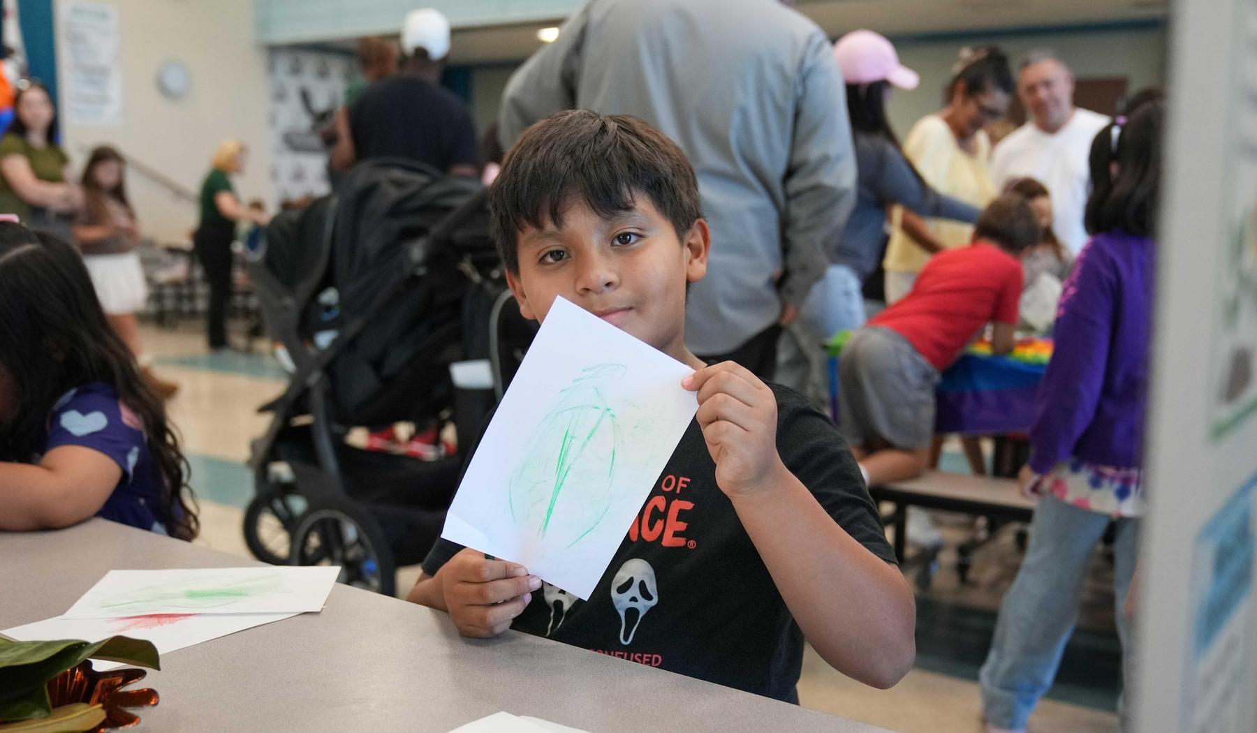 young boy showing his leaf imprint drawing in the school MPR