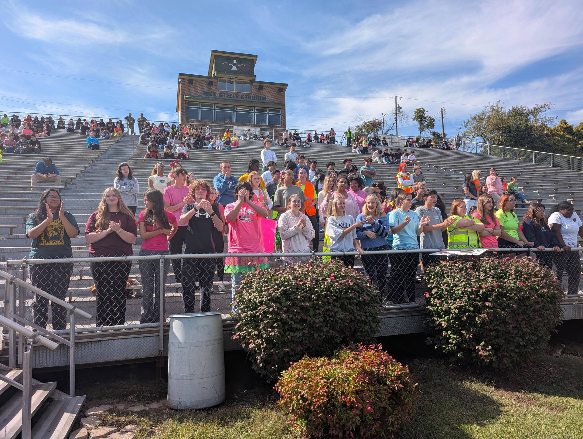 Excited crowd applauding in a stadium during an event.