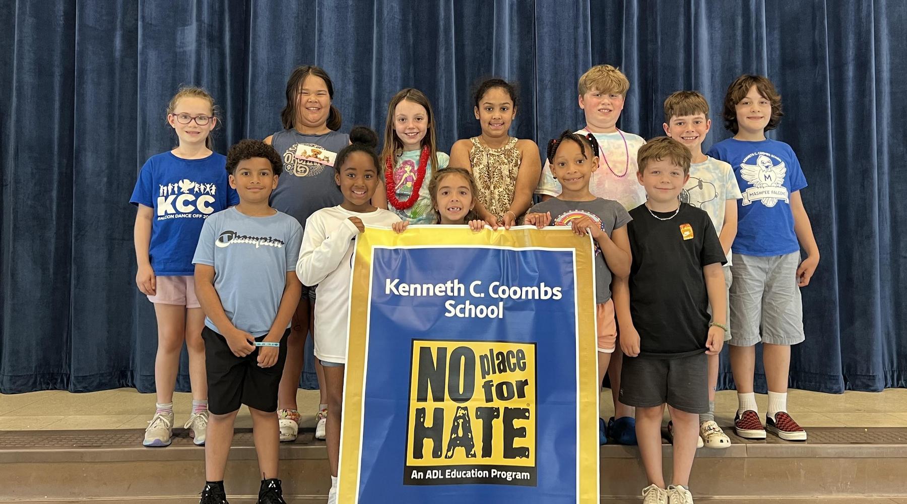 A diverse group of students poses with a banner promoting inclusivity and acceptance.