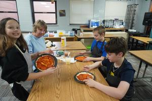 Students show their pizzas are almost ready for the oven.
