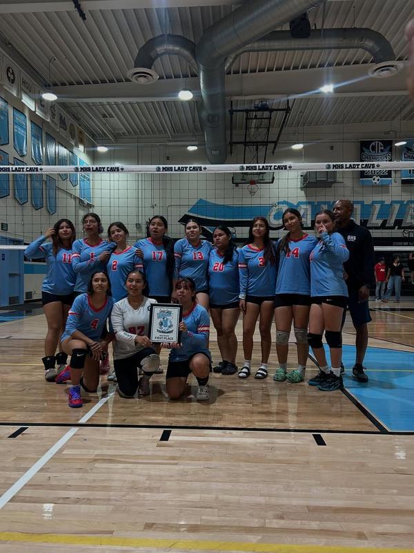 volleyball girls team pose at the end of match inside gymnasium