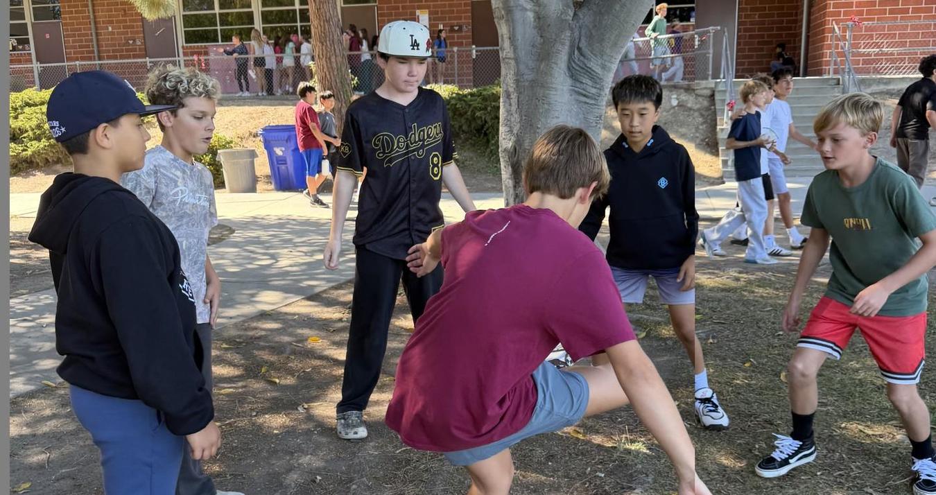 Group of children playing a game outdoors in a schoolyard.