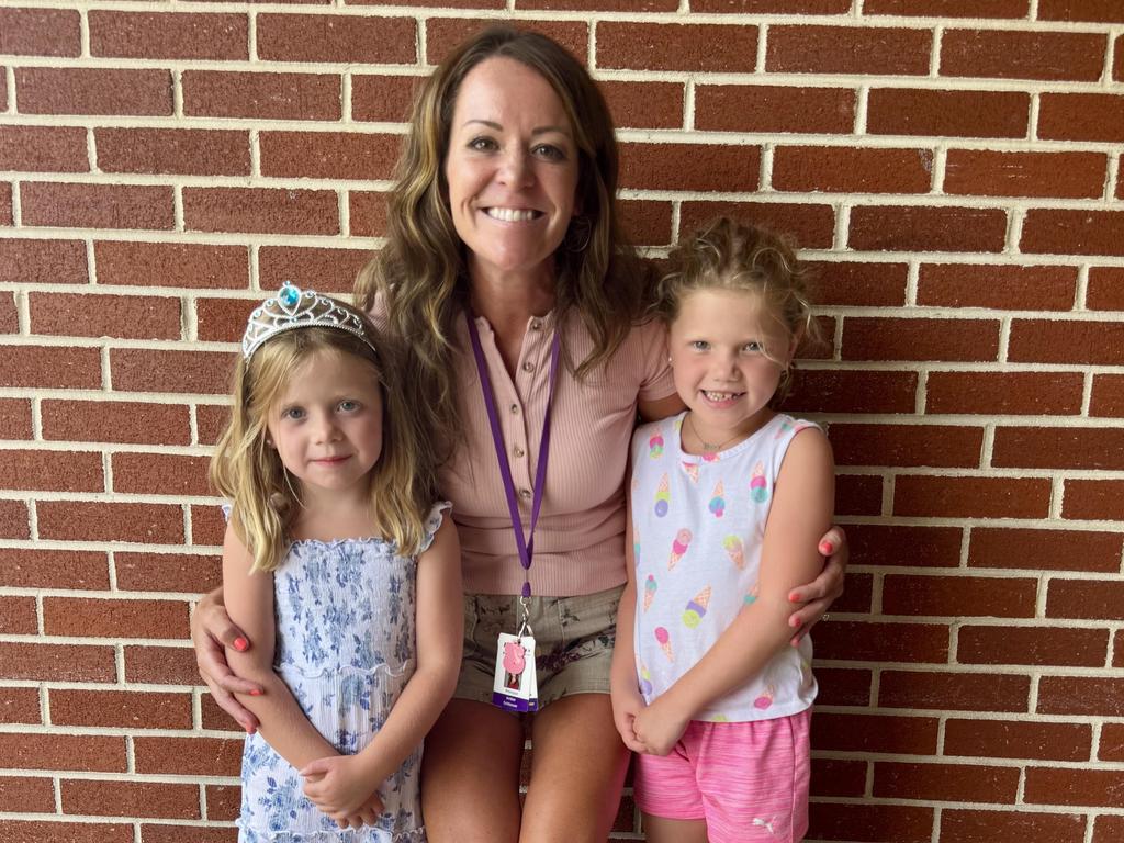 Mrs. Schlosser with two students standing in front of a brick wall outside.