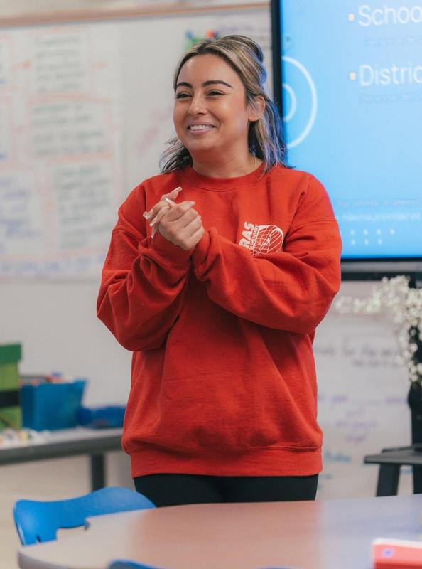person wearing red sweater holding hands in gratitude in classroom
