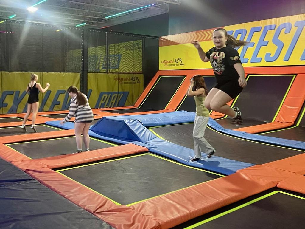 Four students jumping on trampolines.