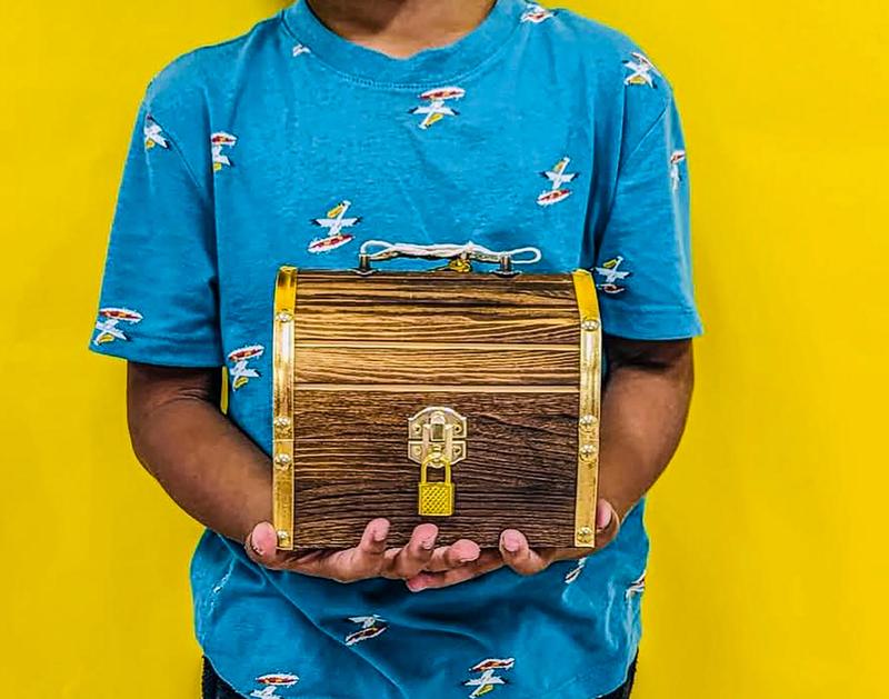 student wearing blue shirt is holding a treasure chest