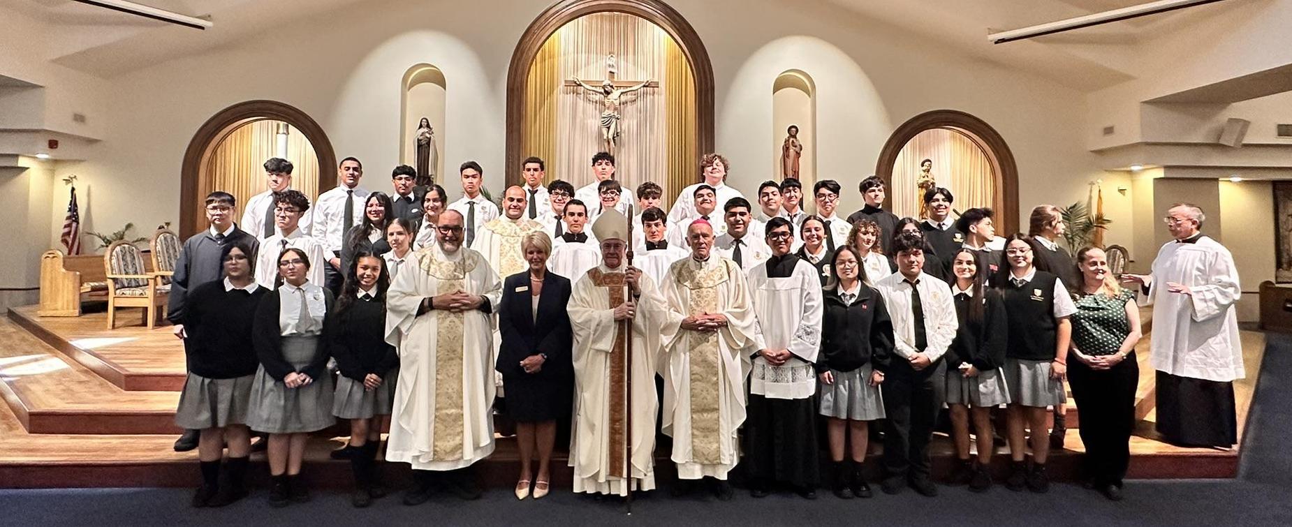 A group of students and clergy posing together inside a church during a ceremony.