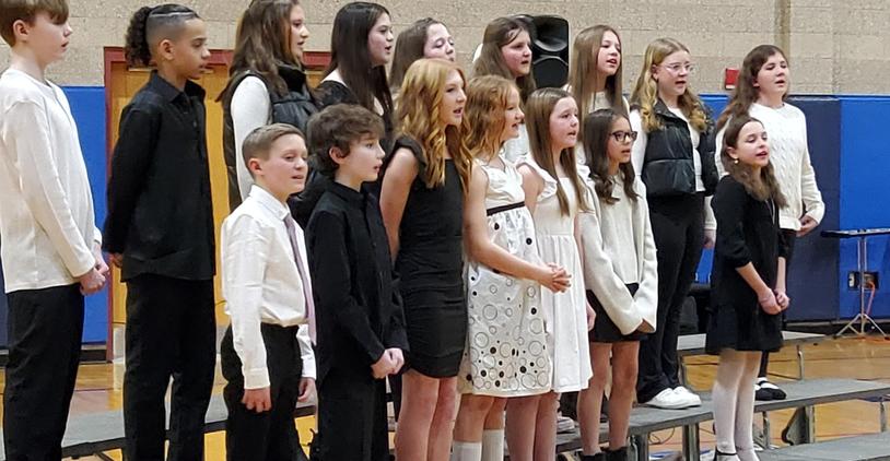 Teenagers singing in unison at a choir performance.