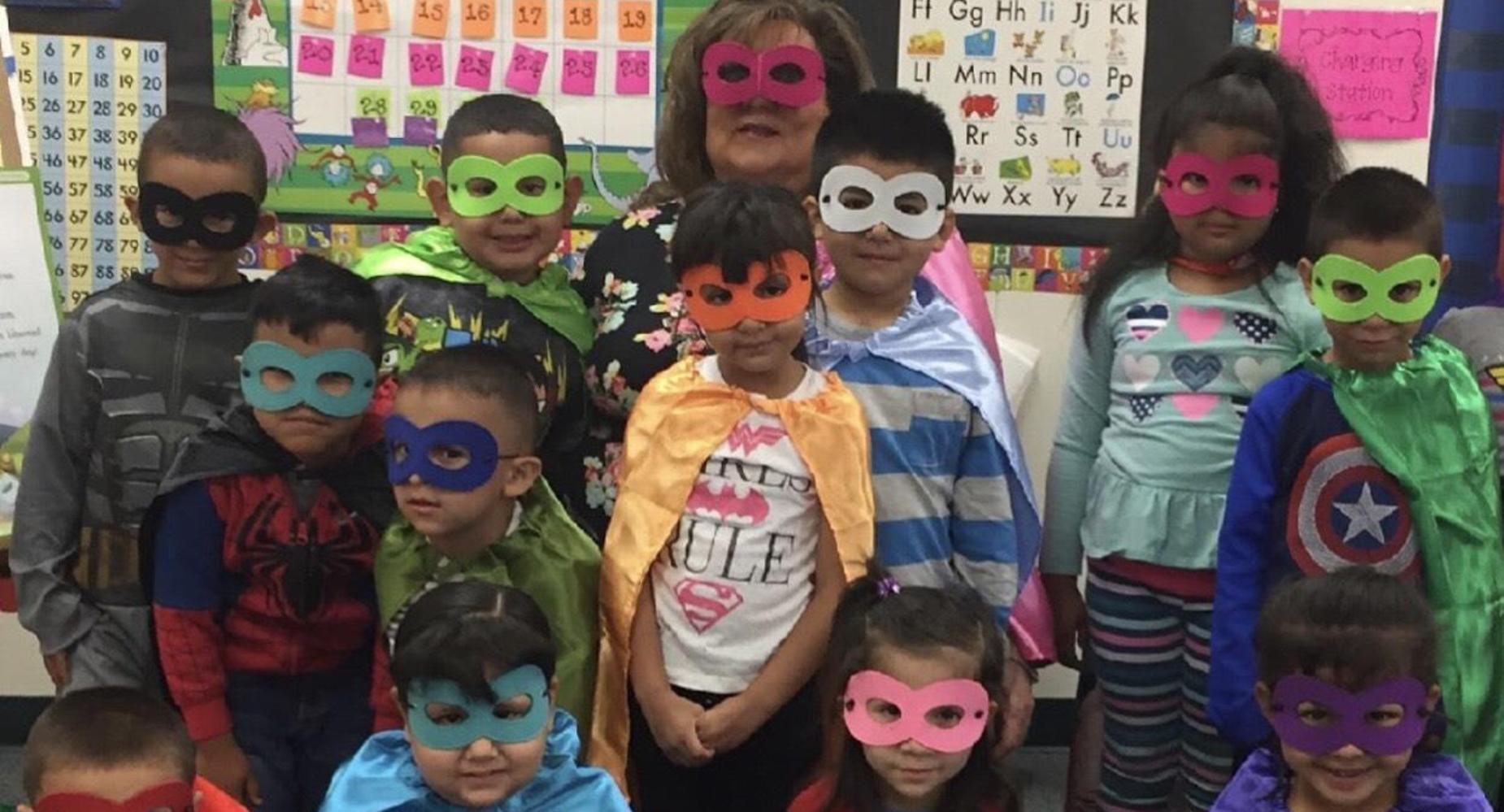 Students with teacher dressed as superheroes.