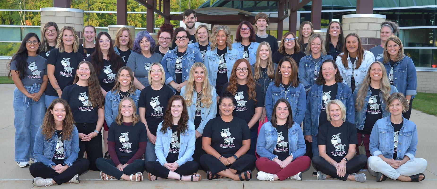 staff outside the entrance in three rows all wearing their BARK shirts featuring a happy bulldog on black material as well as denim shirts and jackets