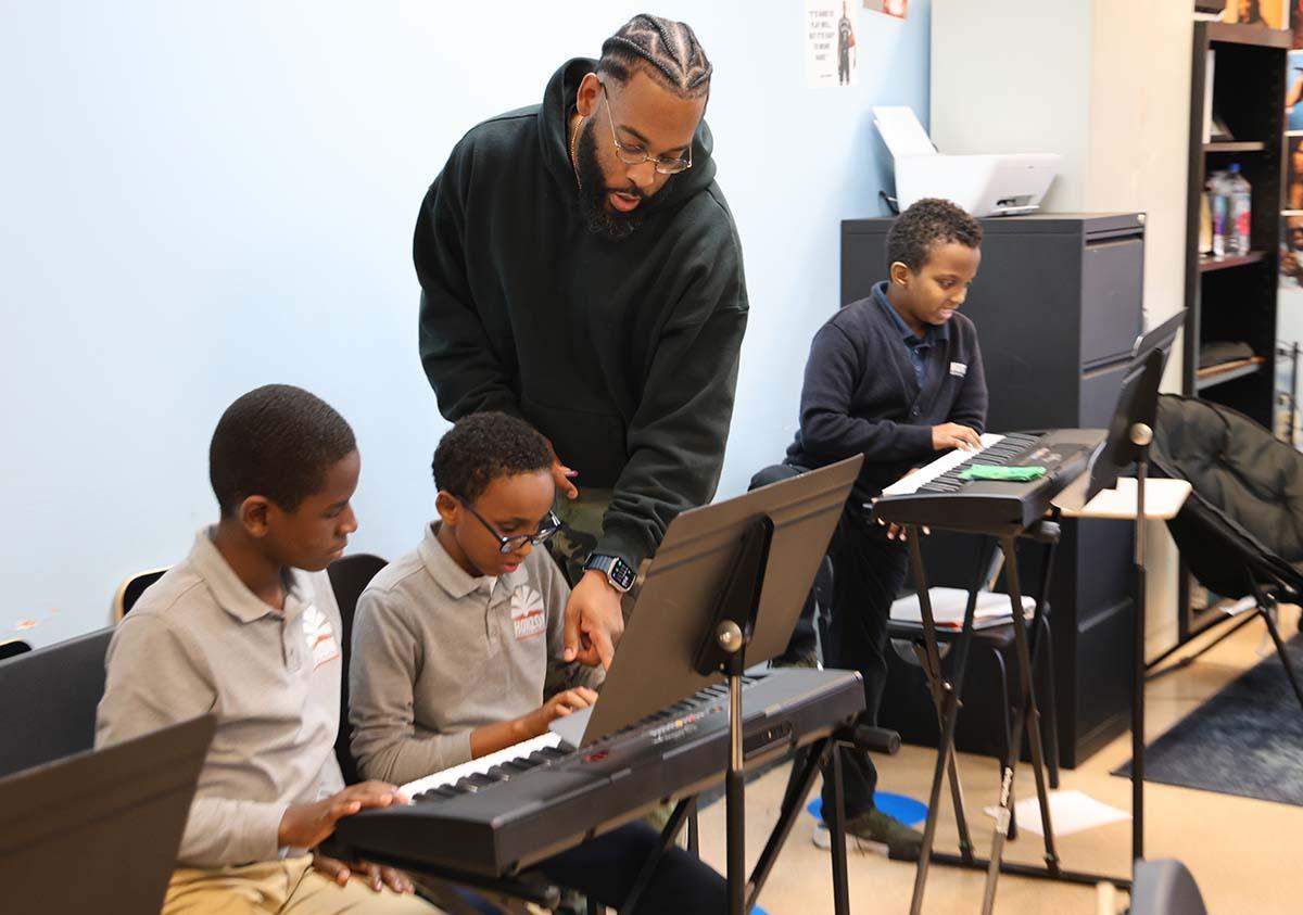 HSA Teacher smiles while kneeling beside a young student in a classroom setting.