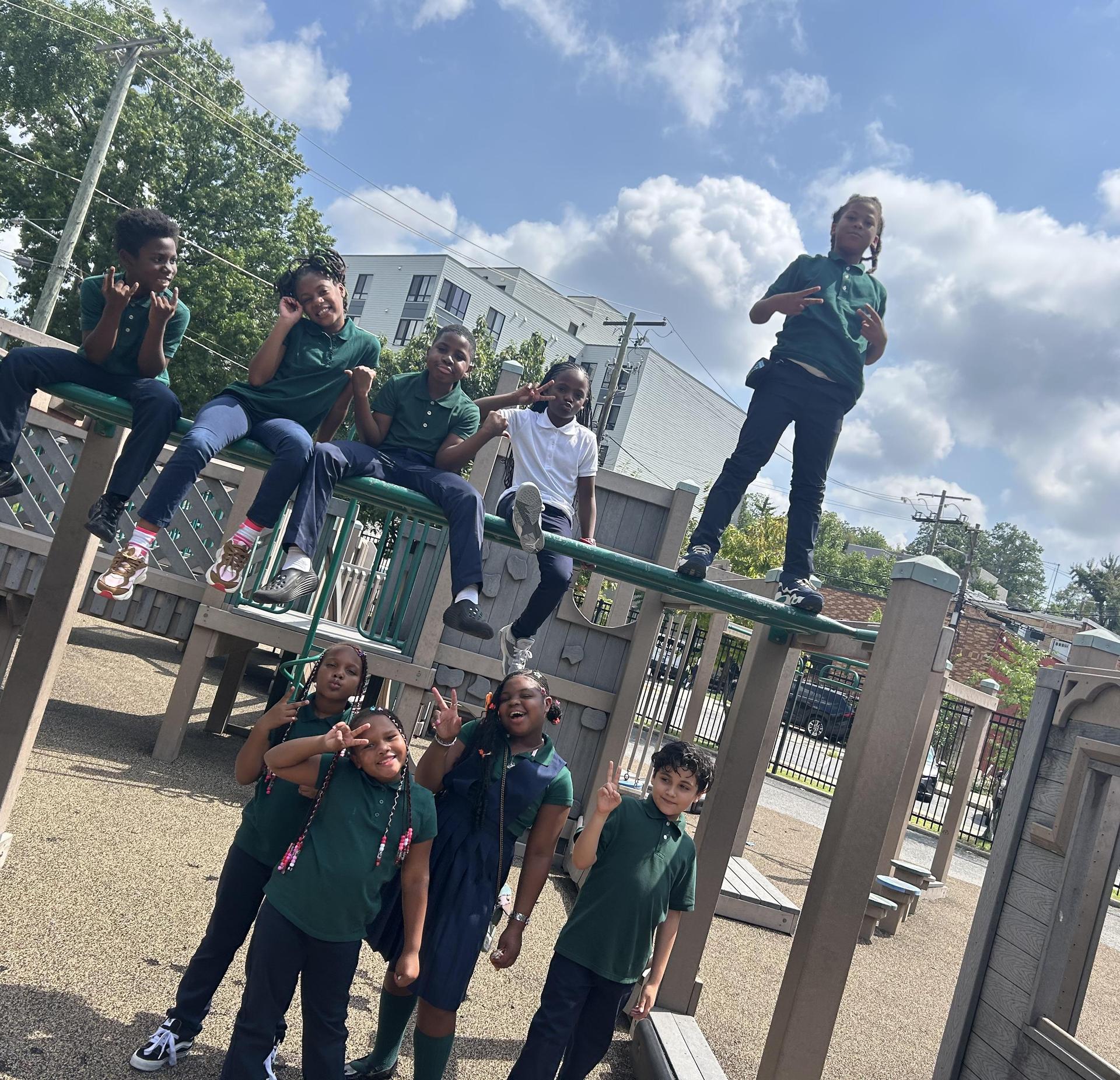 Children playfully posing on a playground structure under a sunny sky.
