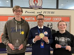 adult standing between two high school students