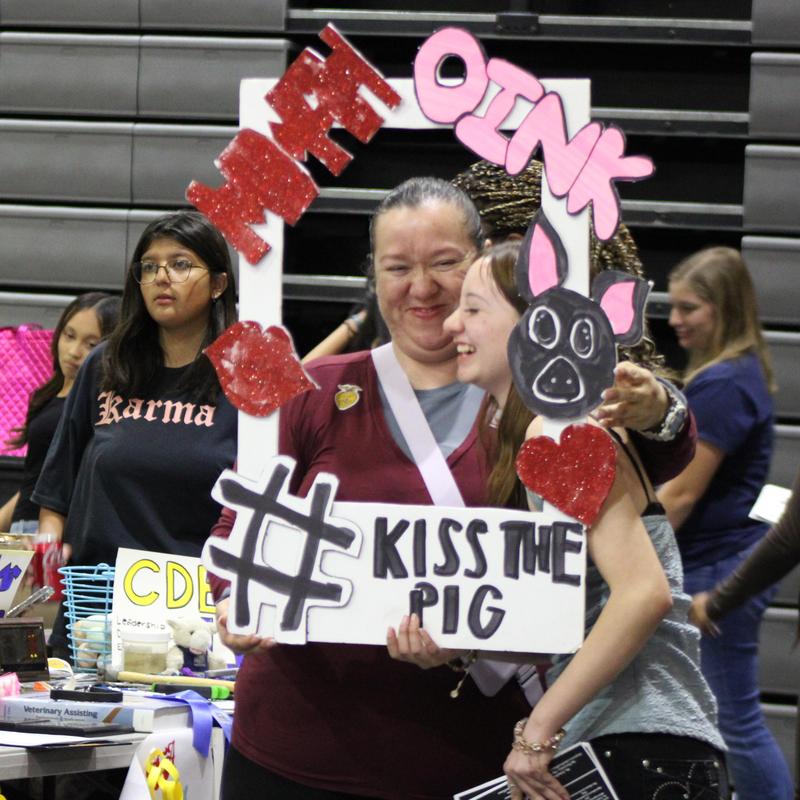 Lady and girl posing with a kiss the pig sign
