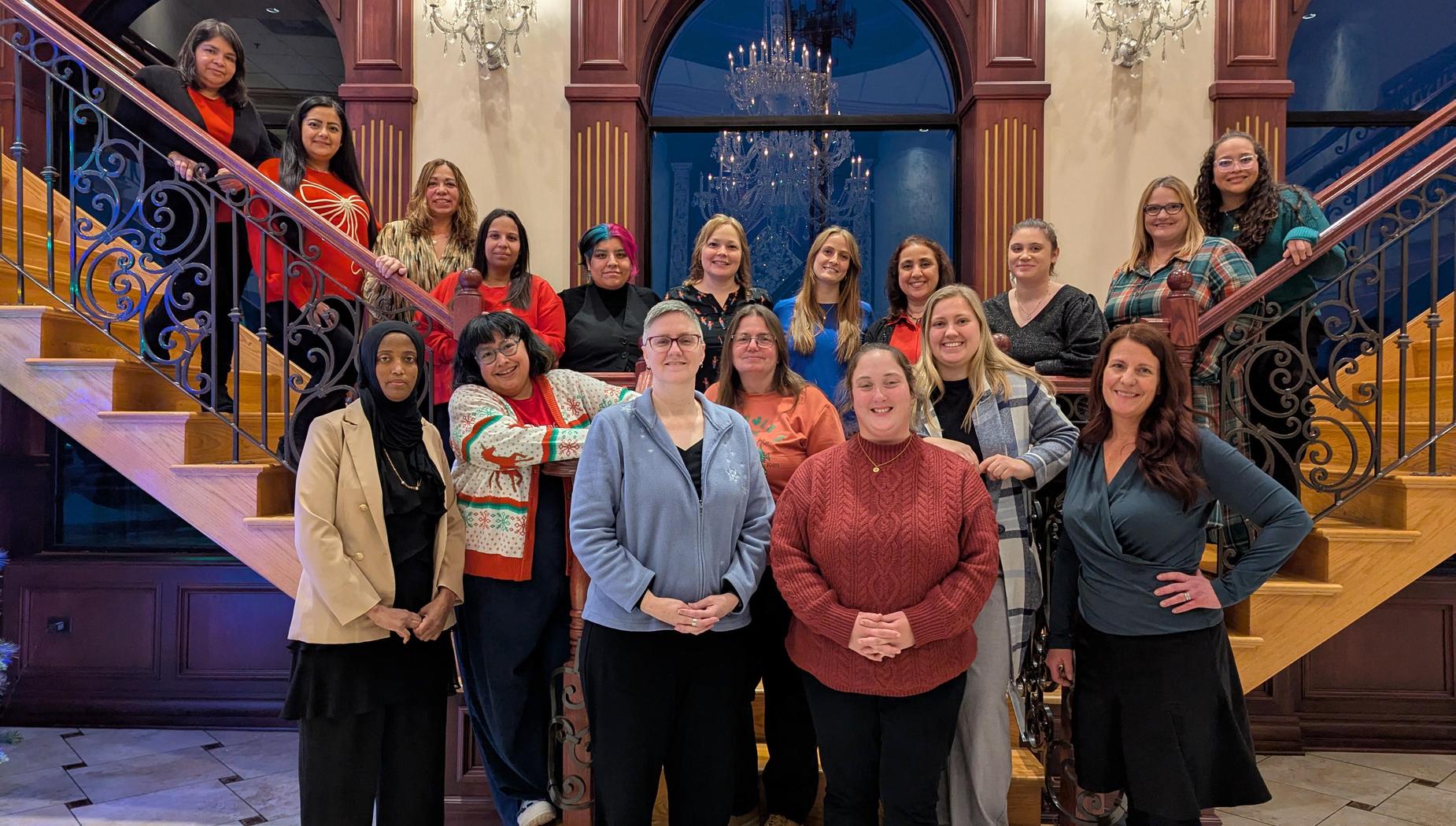 Group of diverse women smiling together in an elegant stairway setting.