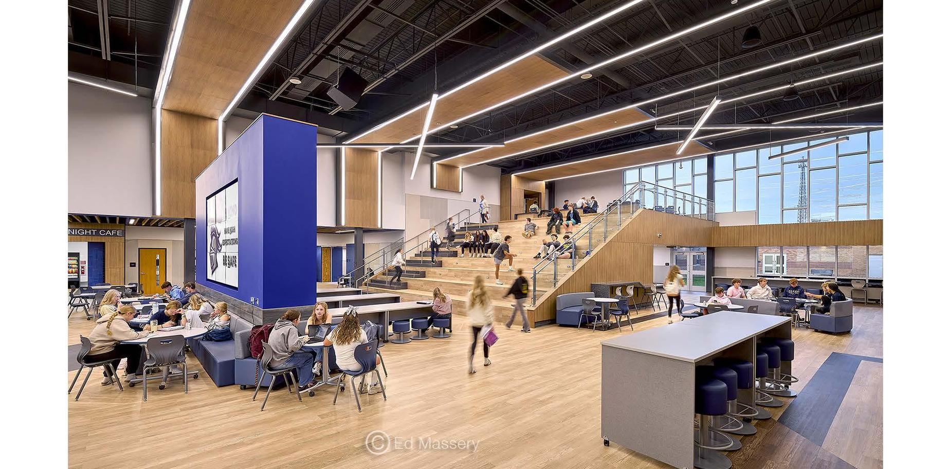 Modern open space with students socializing and stairs in a bright, multi-purpose area.