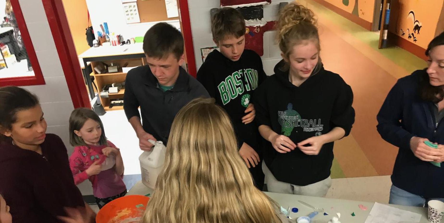 students around table with science experiments