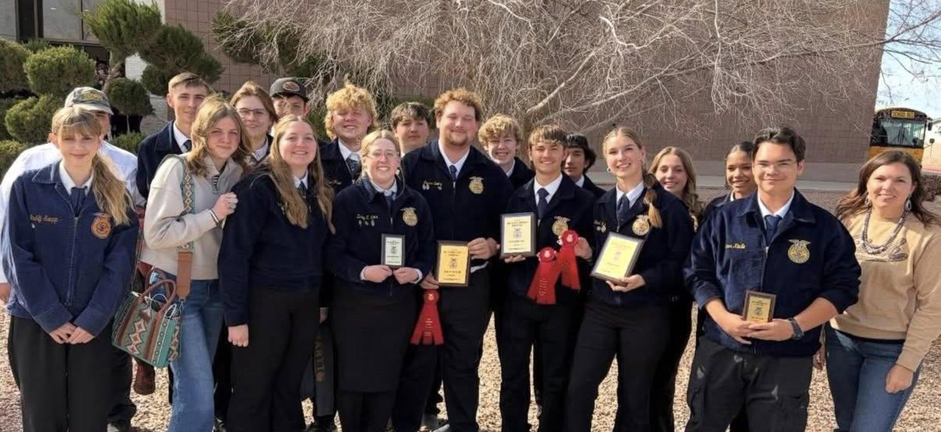Group of students celebrating with awards and ribbons outdoors.