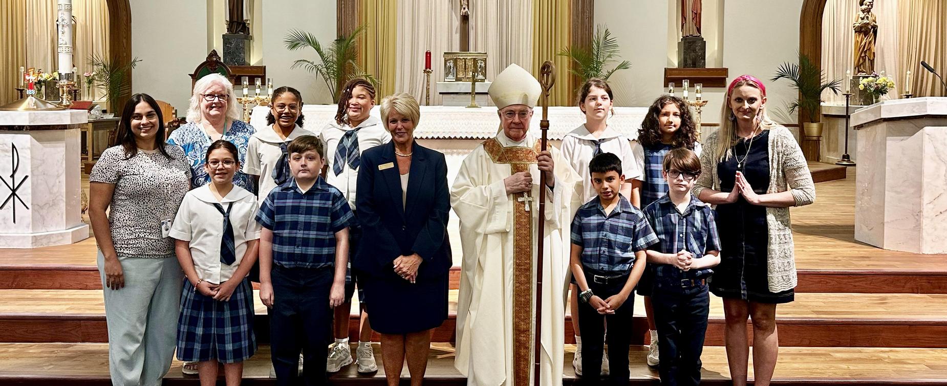 Group of people including clergy and children in a church setting.