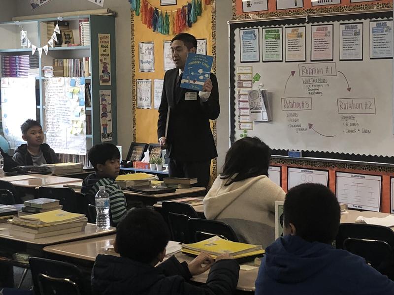 Adults reads Dr. Seuss book to a class of students.