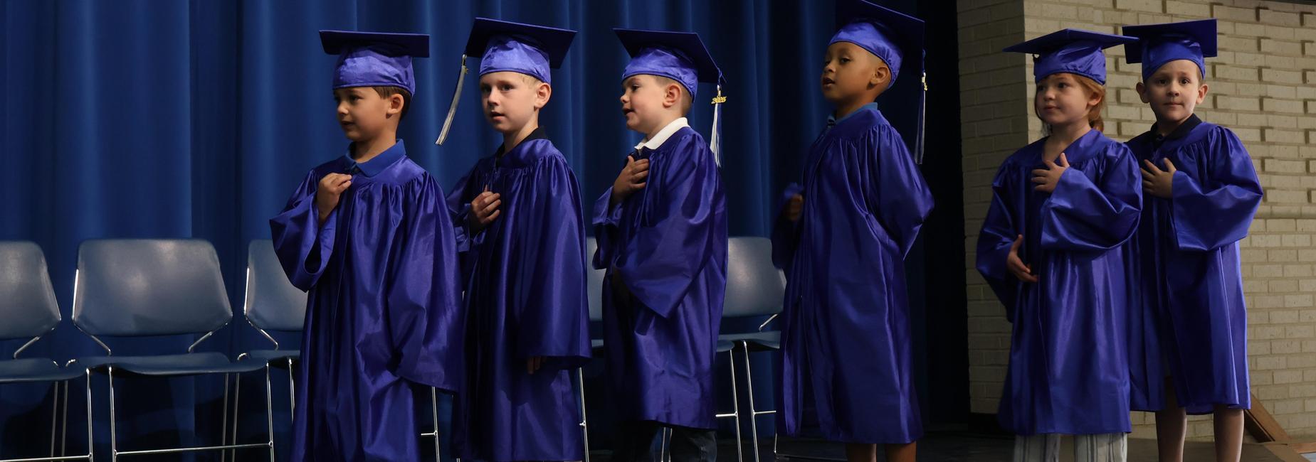Students at Kindergarten graduation did the pledge of allegiance.