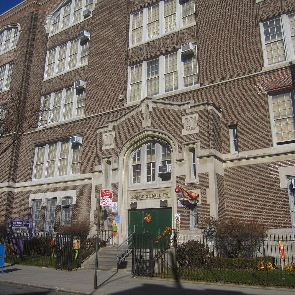 Historic brick school building with decorative entrance and lawn decorations.