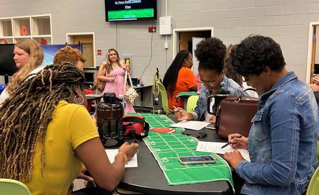 Women concentrating on tasks and collaborating while seated around tables in a library.