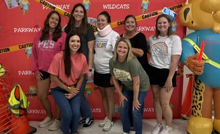 Group photo in front of a red wall with a wildcat and caution elements.