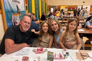 four people are seated in a cafeteria with a donut and milk cartons on the table