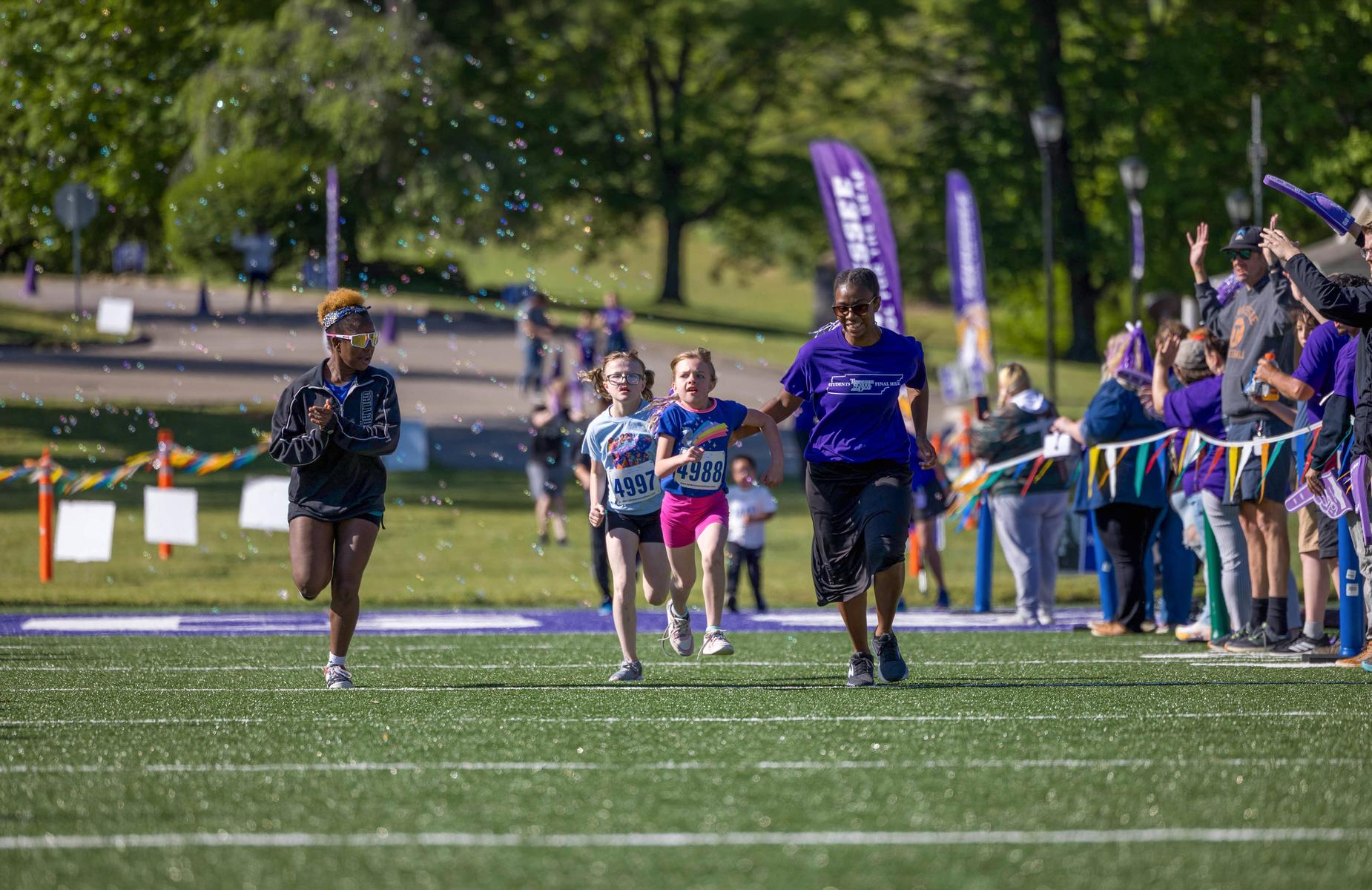 Runners competing in a vibrant outdoor event, surrounded by cheering spectators.